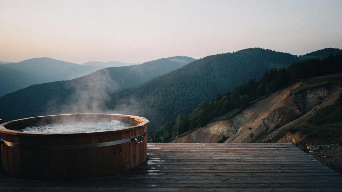 Outdoor spa tub on a timber deck facing the Carpathian ridges at dusk